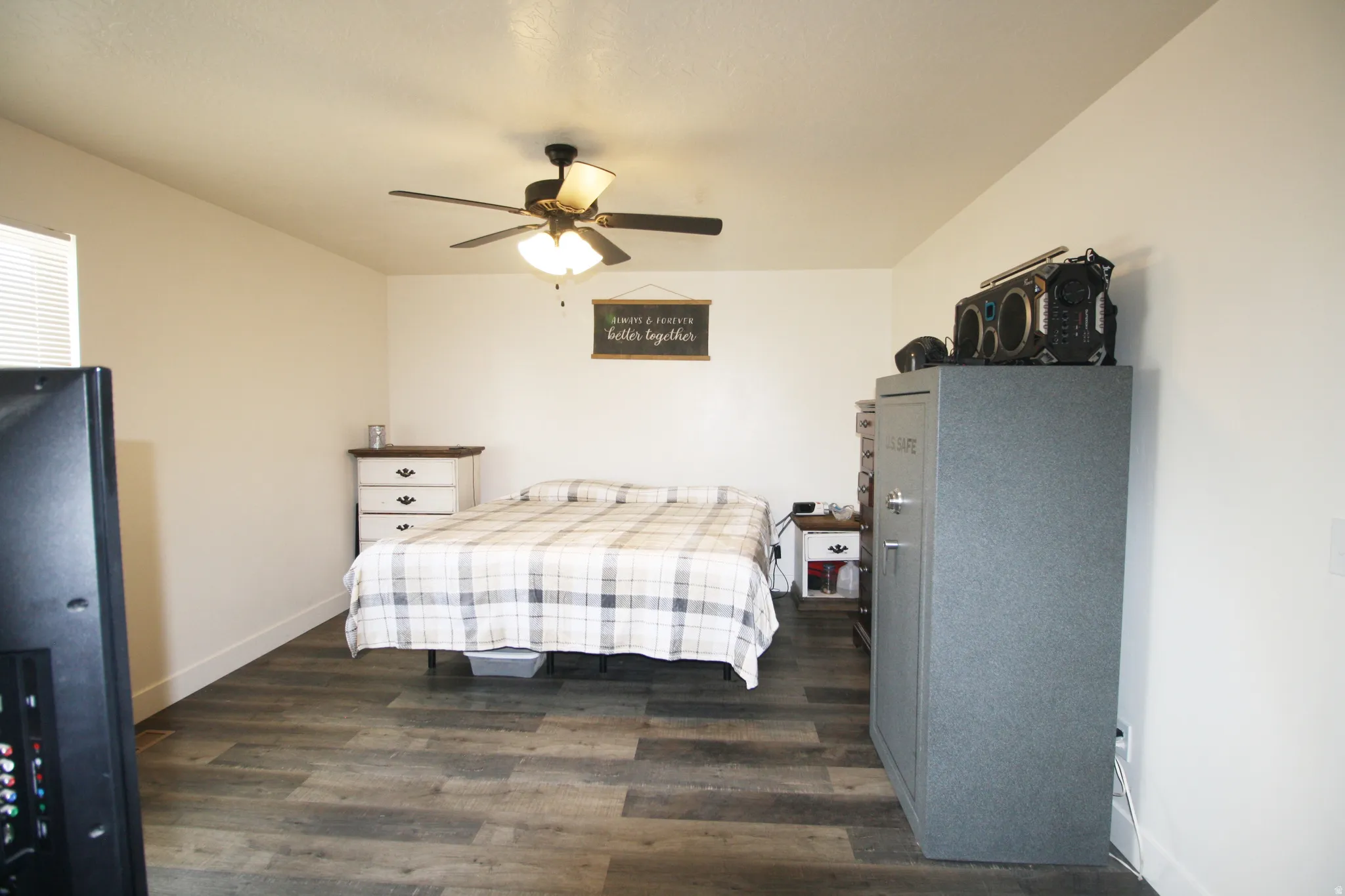 Room with wood-finish flooring, a ceiling fan with integrated lighting, and a white window blind
