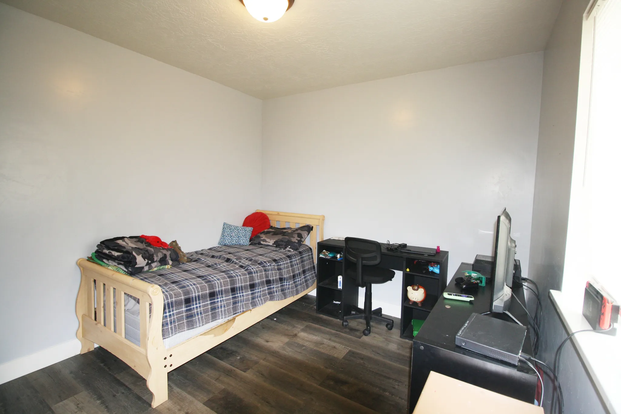 Wall-mounted light fixture, wood-finish flooring, and a window providing natural illumination
