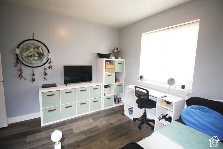Wood-finish flooring, light grey wall paint, and a built-in desk with integrated shelving