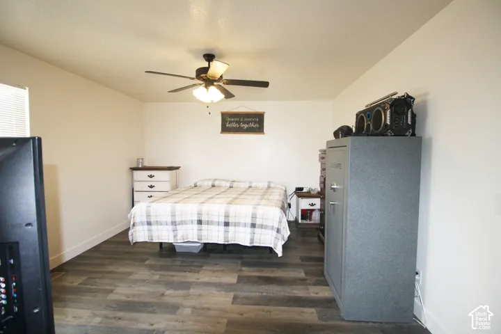 Room with wood-finish flooring, a ceiling fan with integrated lighting, and a white window blind