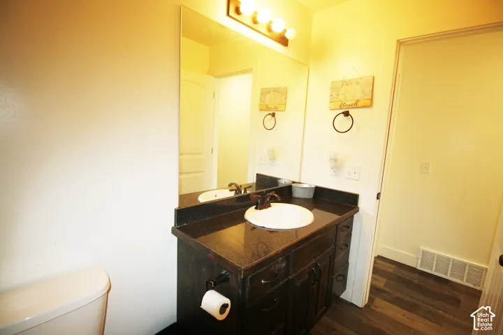 Dark wood-finish vanity with a single basin sink, bronze-finish faucet, and a large wall-mounted mirror