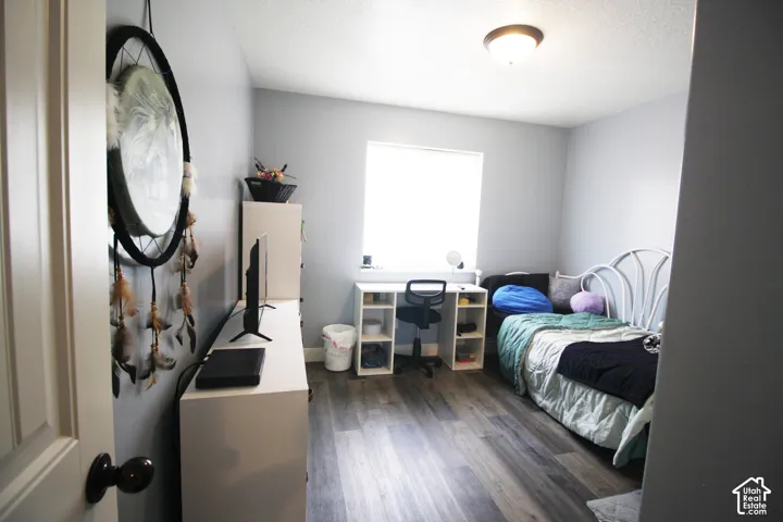 Wood-finish flooring with a ceiling-mounted light fixture, and a window with a roller shade