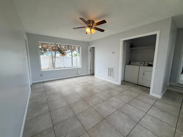 Tiled flooring, ceiling fan with integrated lighting, laundry closet with shelving, and large window
