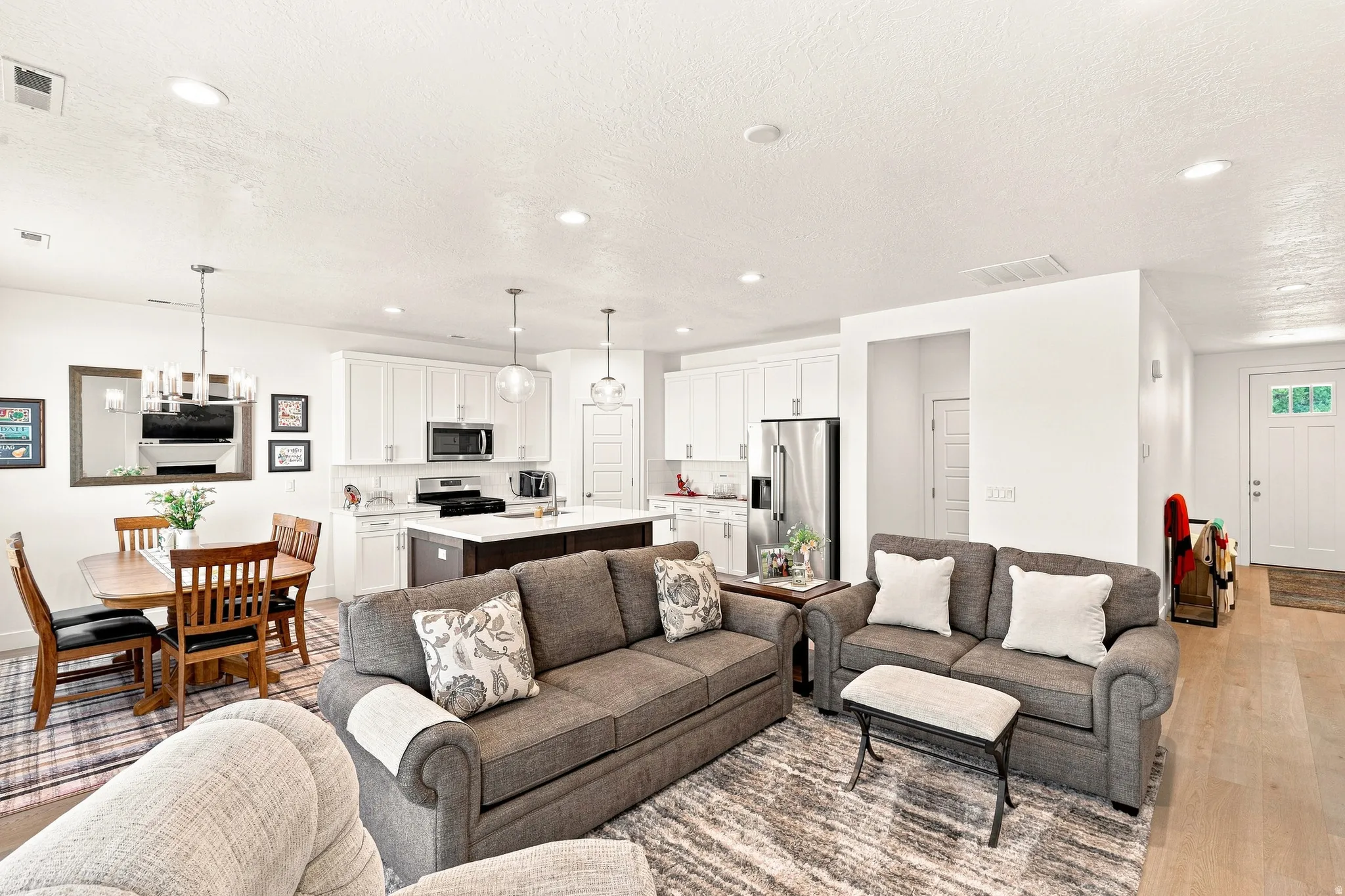Open-concept living and dining area featuring hardwood flooring, recessed ceiling lighting, and stainless steel appliances