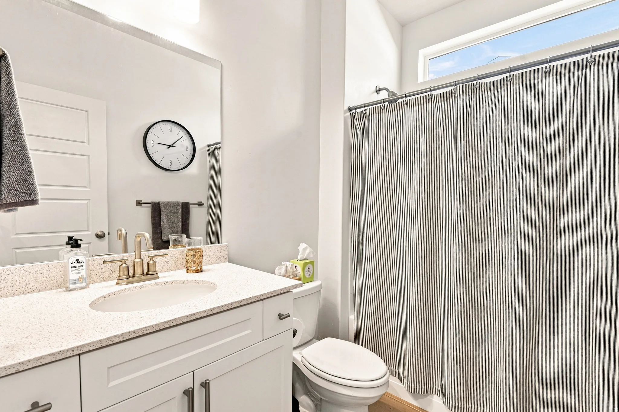 Spa-inspired bathroom featuring a white vanity with quartz countertop, polished brass fixtures, and ample storage