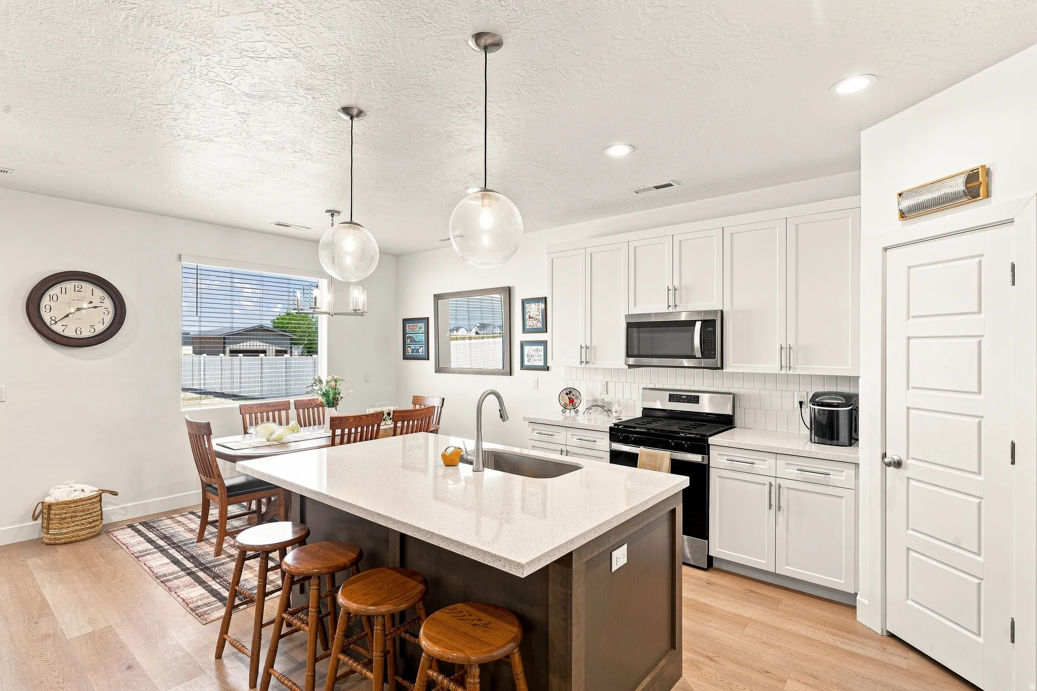 Kitchen featuring a central island with countertop, white shaker-style cabinetry, stainless steel appliances, and wood-finish flooring