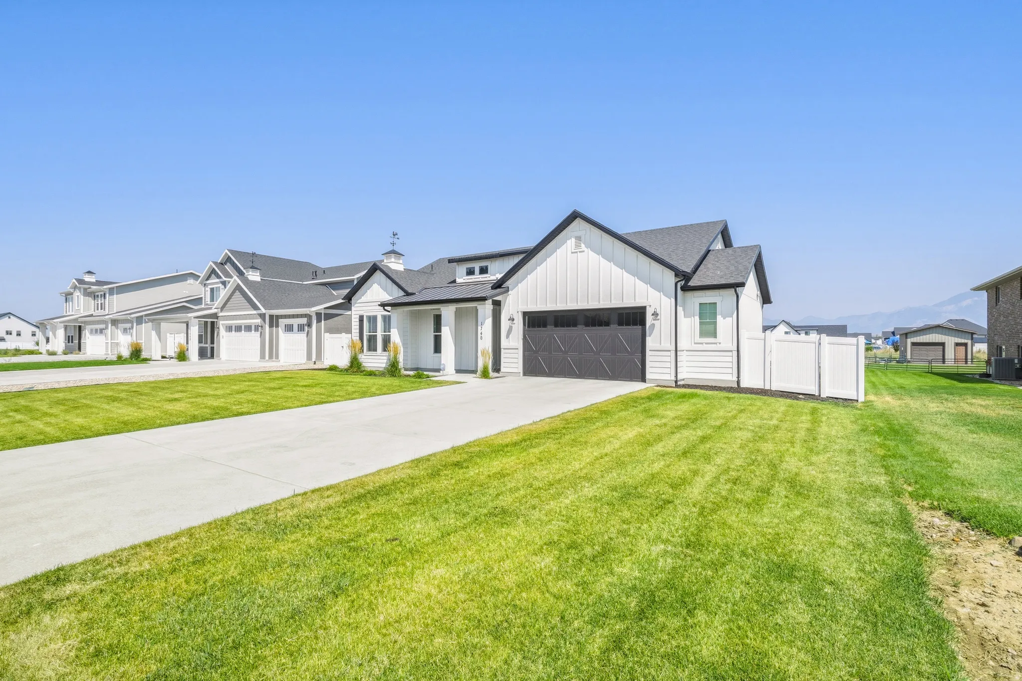 Modern farmhouse featuring a clean-lined exterior with board-and-batten siding, multiple gabled rooflines, and a two-car garage with dark panel detailing