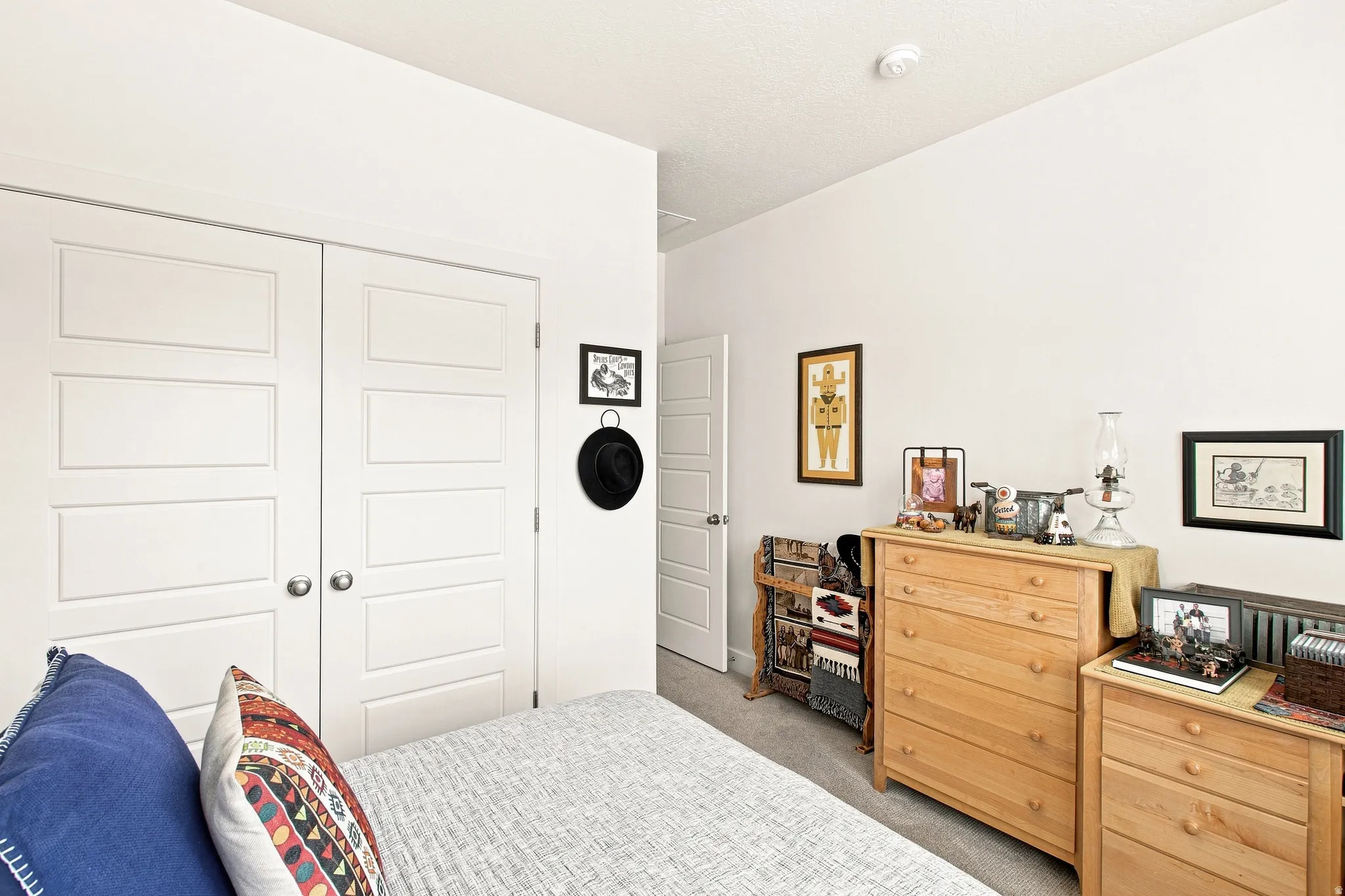 Bright secondary bedroom with white six-panel closet doors, wood-finish dresser with integrated storage, and plank flooring throughout