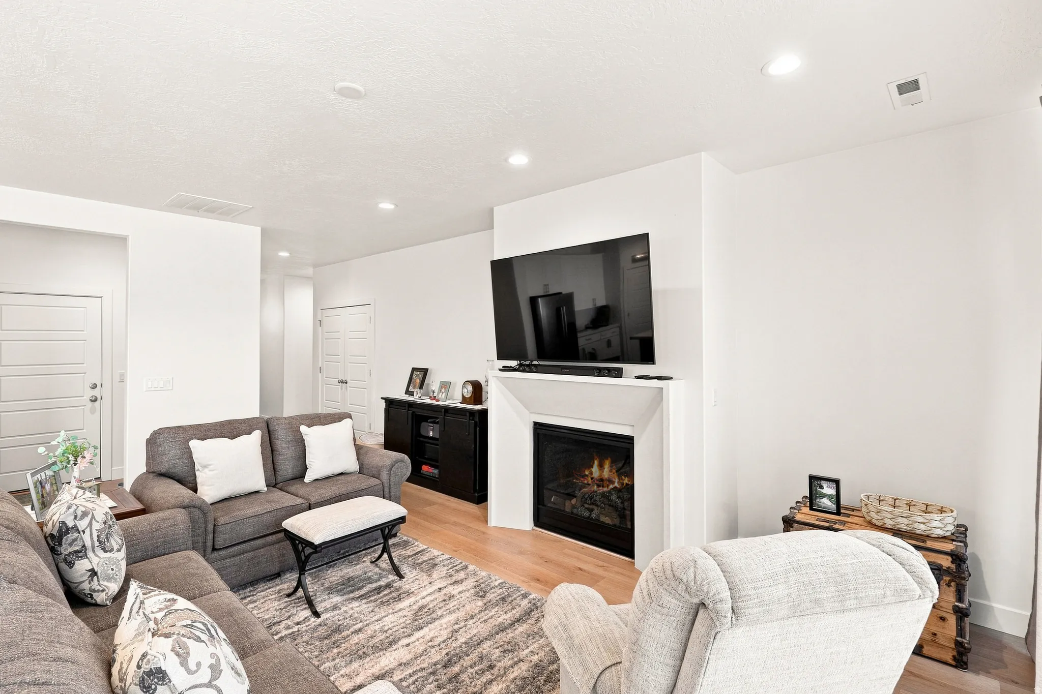 Recessed lighting, wood-finish flooring, white walls, and fireplace with mantel