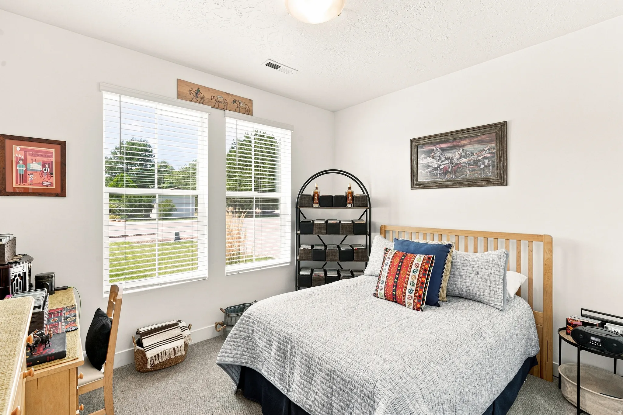Bright secondary bedroom featuring large dual-pane windows with plantation shutters, wood-finish flooring, and ample natural light