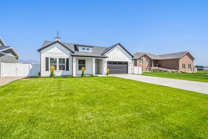 Modern farmhouse exterior featuring a clean-lined facade with board-and-batten siding, multiple gabled rooflines with architectural detail, and a two-car garage