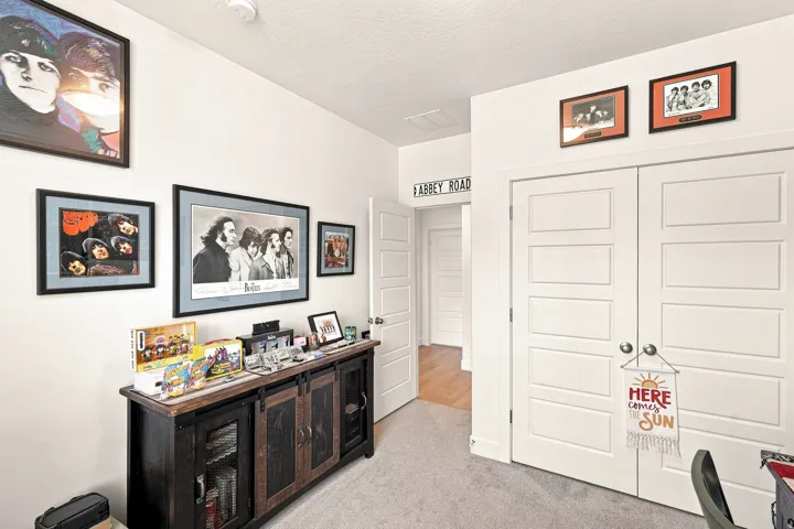 Dedicated media room featuring recessed ceiling lighting, dark wood-finish cabinetry with glass-front display storage, framed artwork throughout, and dual white six-panel closet doors