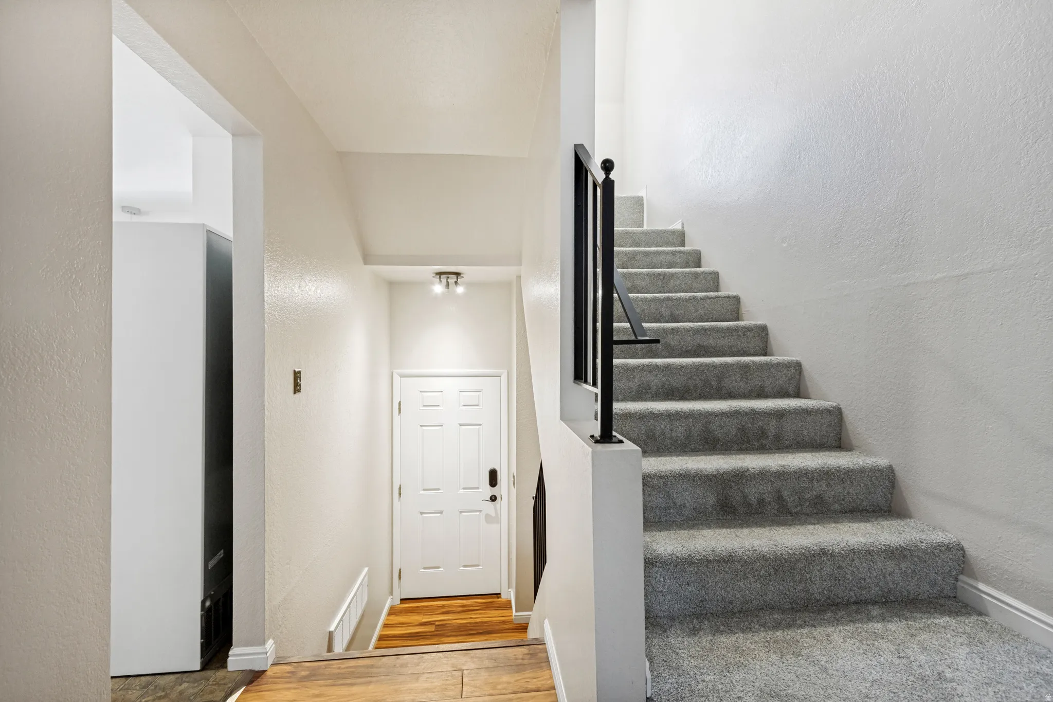 Entryway featuring wood-finish flooring, a white paneled door, and an overhead light fixture