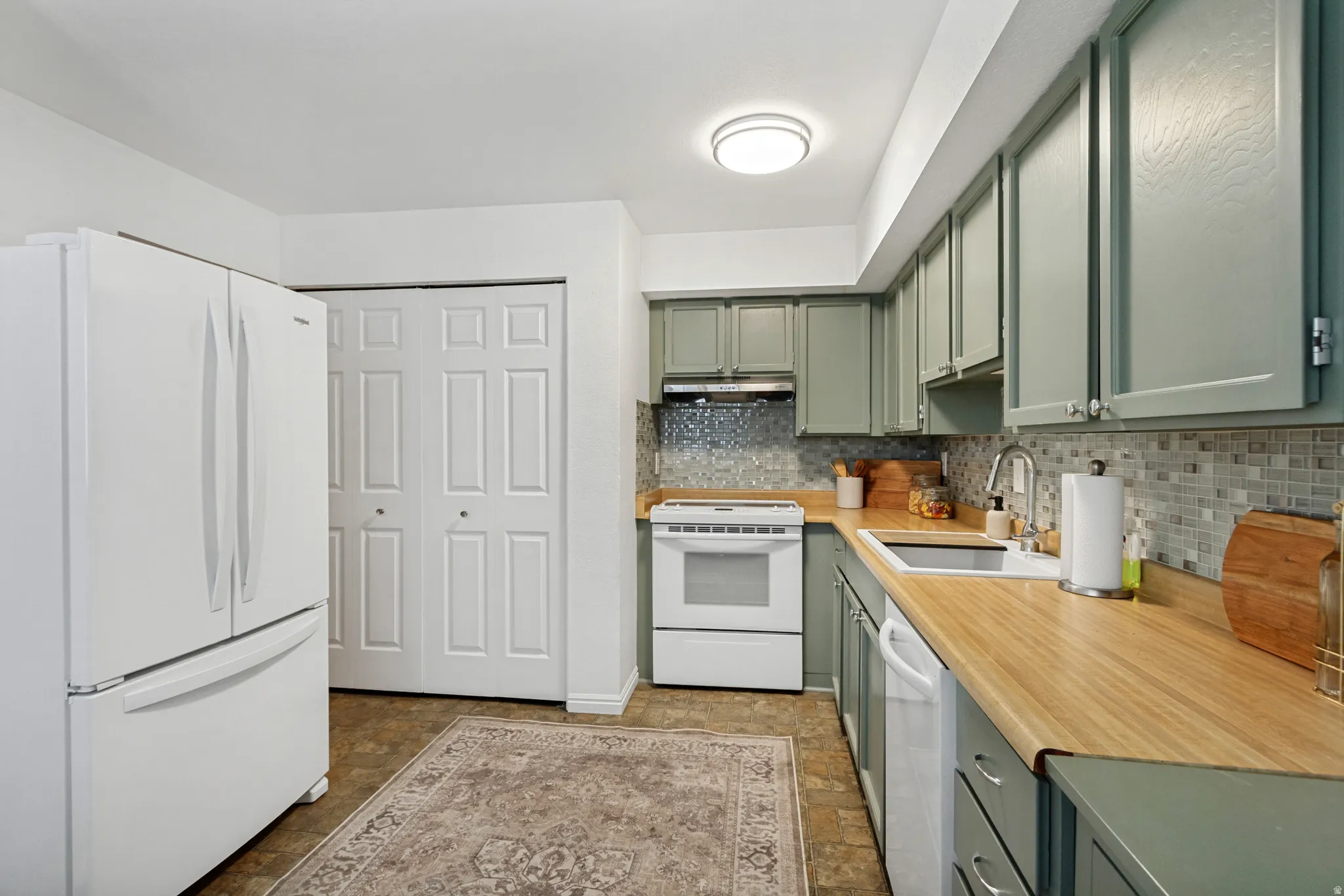 Kitchen featuring wood-finish countertops, mosaic tile backsplash, and painted cabinetry