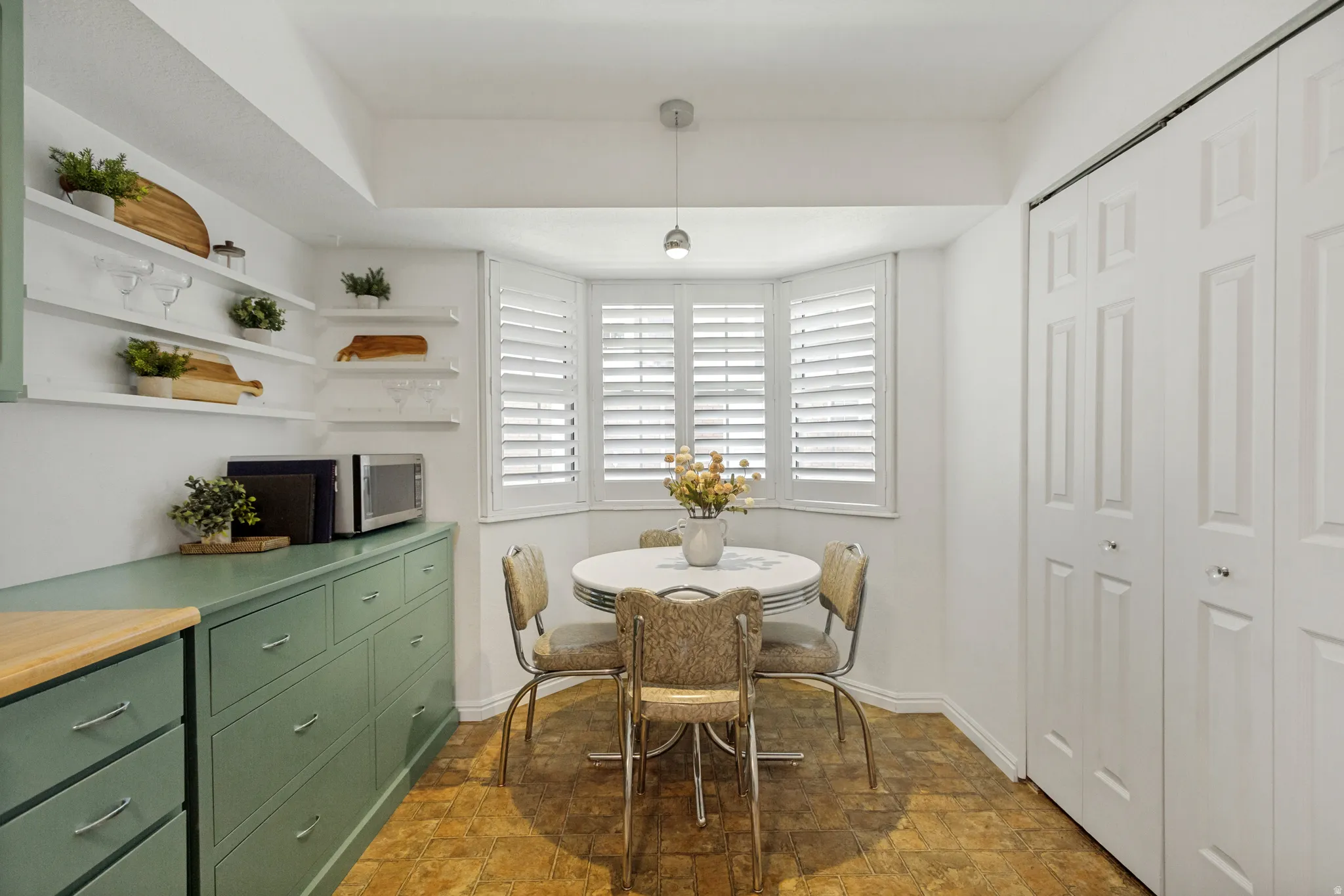 Bay window with white plantation shutters, built-in shelving, painted cabinetry and bi-fold pantry doors