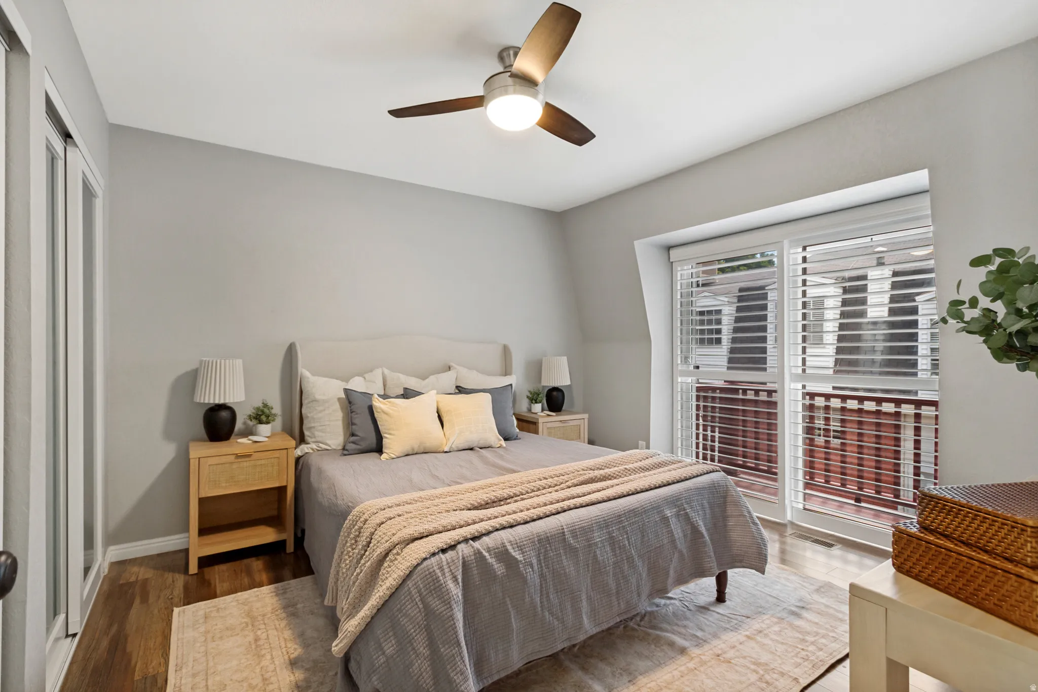 Wood-finish flooring, ceiling fan, white wall paint, and sliding glass doors to balcony.