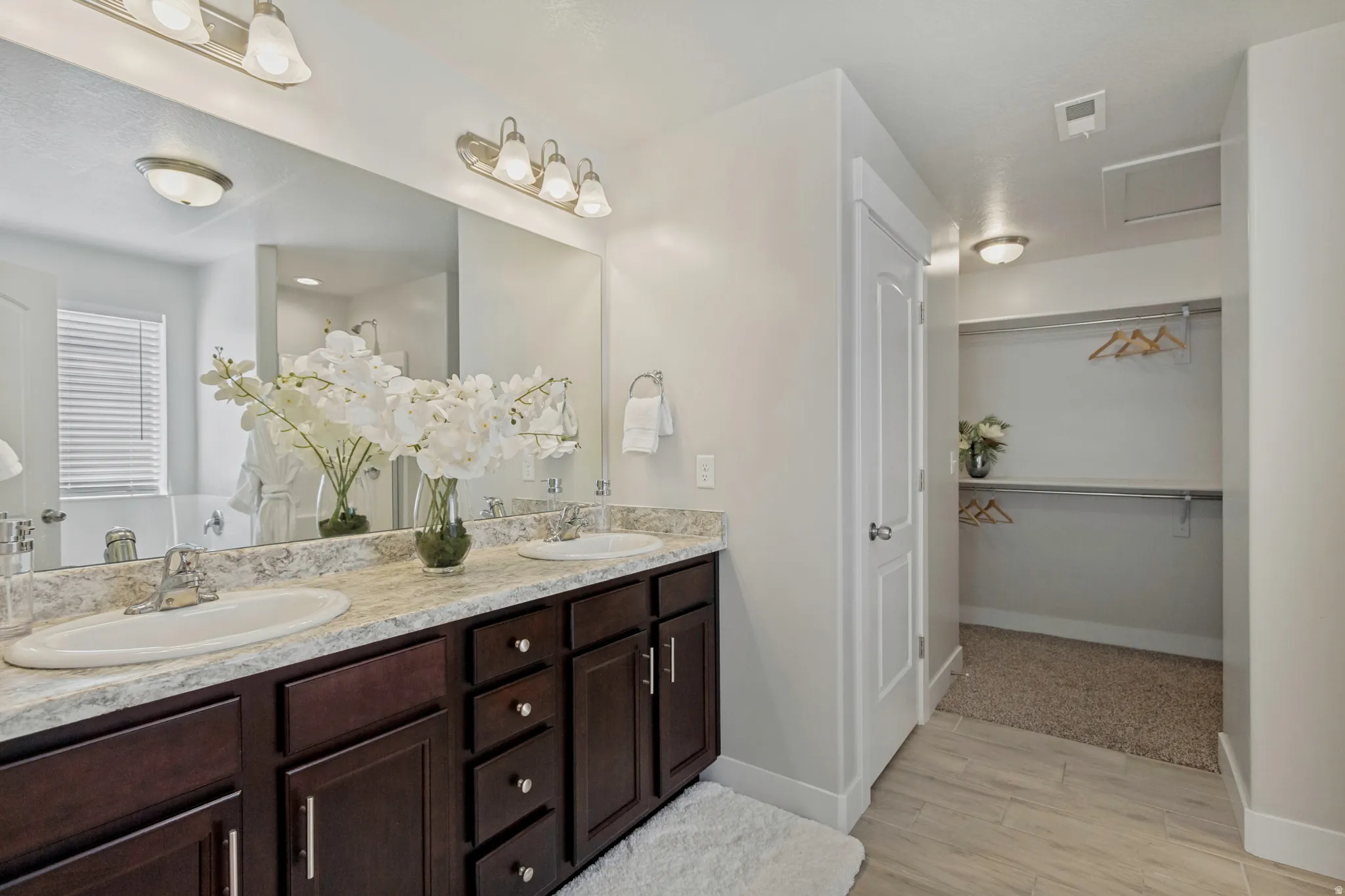 Dual vanity with dark wood-finish cabinetry, light-toned countertop, and undermount sinks
