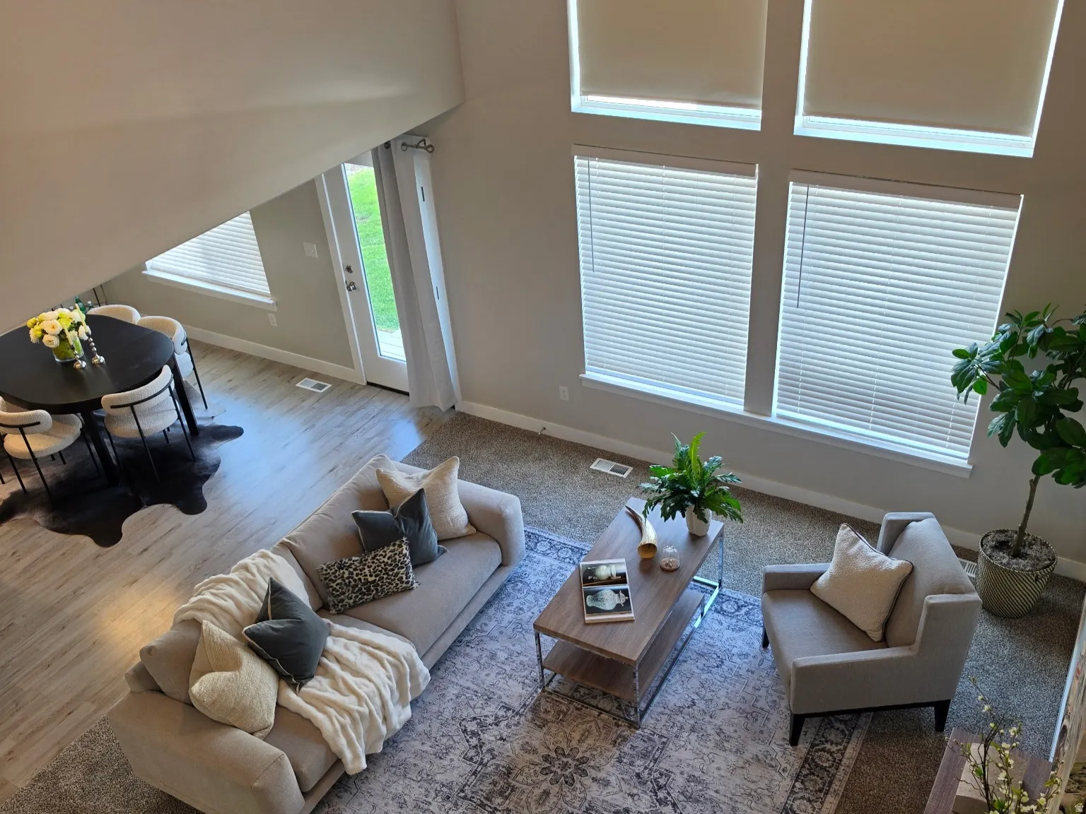 Vaulted ceilings with a ceiling fan, multiple large windows, and a glass-paneled door