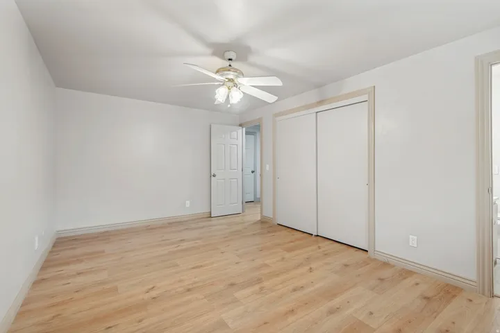 Wood-finish flooring, white walls, and a ceiling fan with integrated lighting