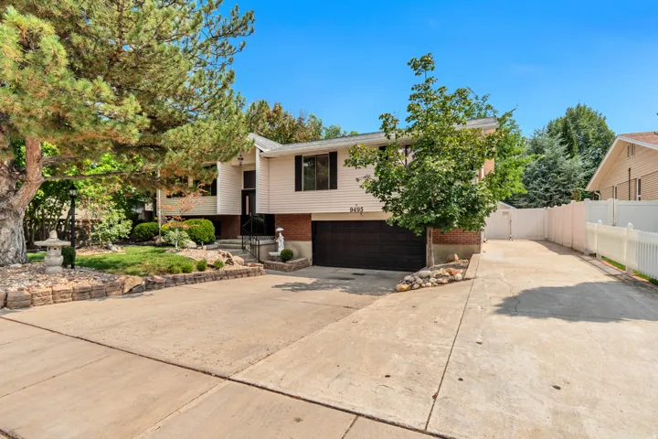 Split-level residence featuring a two-car garage, concrete driveway, and white picket fencing