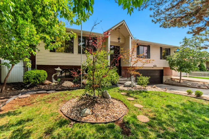 Split-level residence featuring a prominent front entrance, attached garage, and a sloped driveway