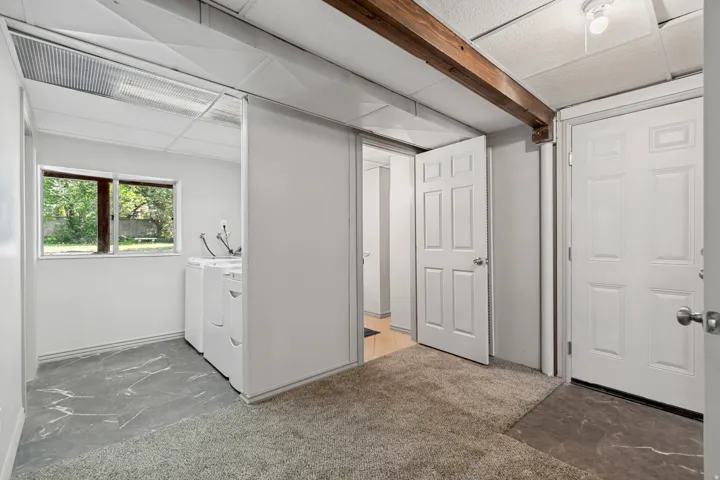Laundry area featuring a window, tile flooring, and exposed wood beam