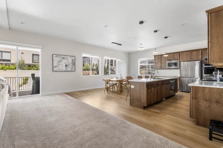 Open-concept living space featuring wood-finish flooring, recessed lighting, and a kitchen island with seating