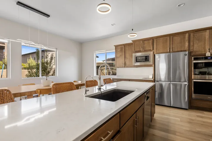 Kitchen featuring a large island with a sink, stainless steel appliances, wood-finish flooring, and recessed lighting
