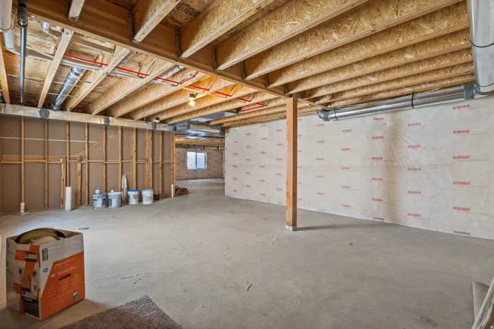Unfinished basement with exposed ceiling joists, concrete flooring, and partial framing