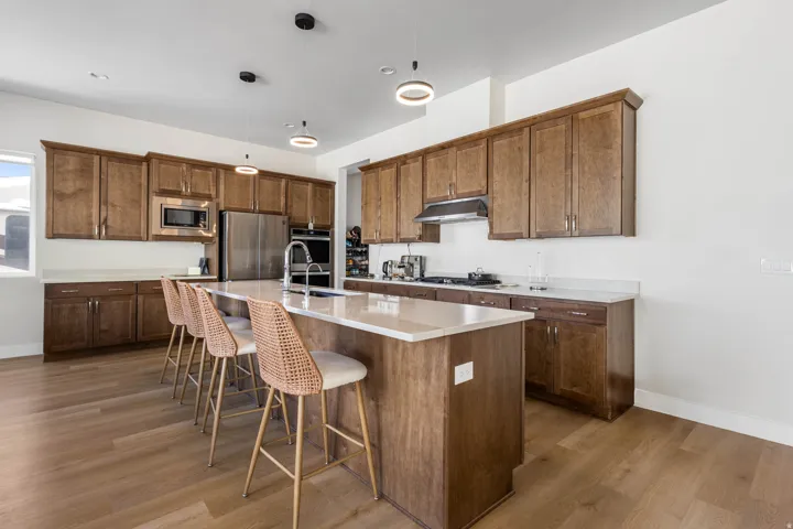 Kitchen featuring wood-finish flooring, an island with countertop seating, stainless steel appliances, dark wood cabinetry, and recessed lighting