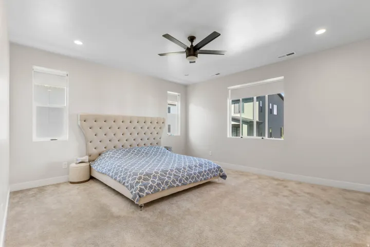 Spacious room featuring neutral carpet, recessed lighting, and multiple windows with roller shades