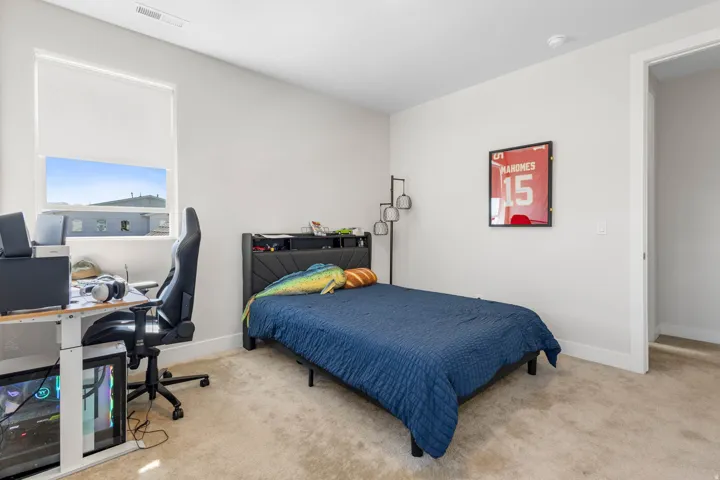 Carpeted room featuring a window with a roller shade, light-toned walls, and a white trim