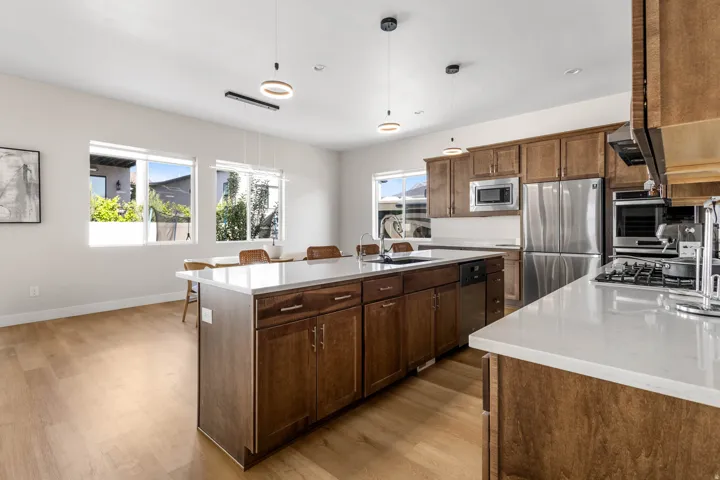 Open-concept kitchen featuring wood-finish cabinetry, stainless steel appliances, and a central island with a white countertop