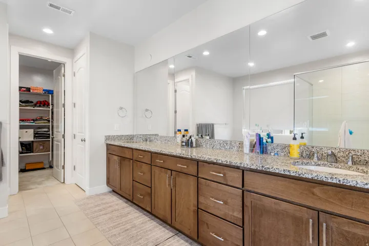 Double vanity with wood-finish cabinetry, granite-style countertop, and dual integrated sinks
