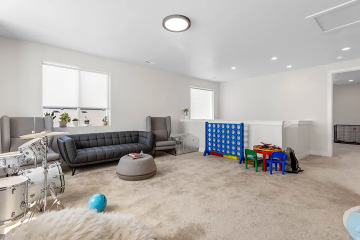 Spacious carpeted room featuring white walls, multiple windows, recessed lighting, and a white railing