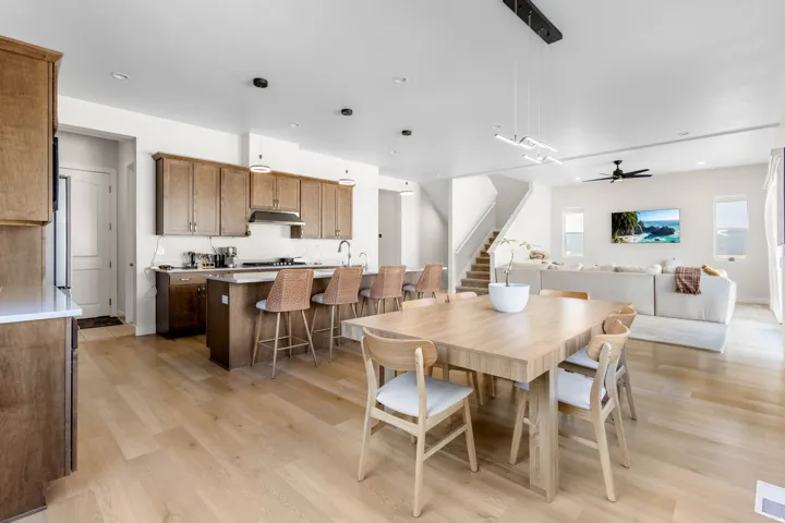 Open-concept living space featuring wood-finish flooring, a kitchen island with seating, dark wood cabinetry, and a modern ceiling fan