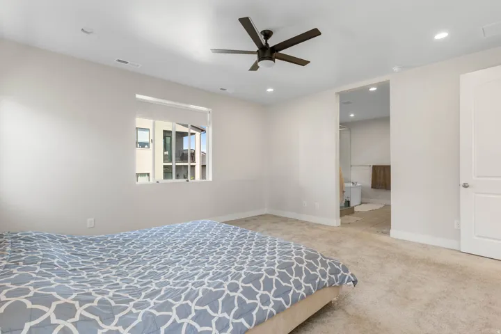 Recessed lighting, wood-finish ceiling fan, window with roller shade, carpeted flooring, and a flat-panel door