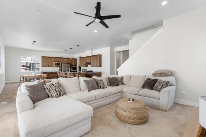 Open-concept living space featuring a ceiling fan, recessed lighting, and stair access