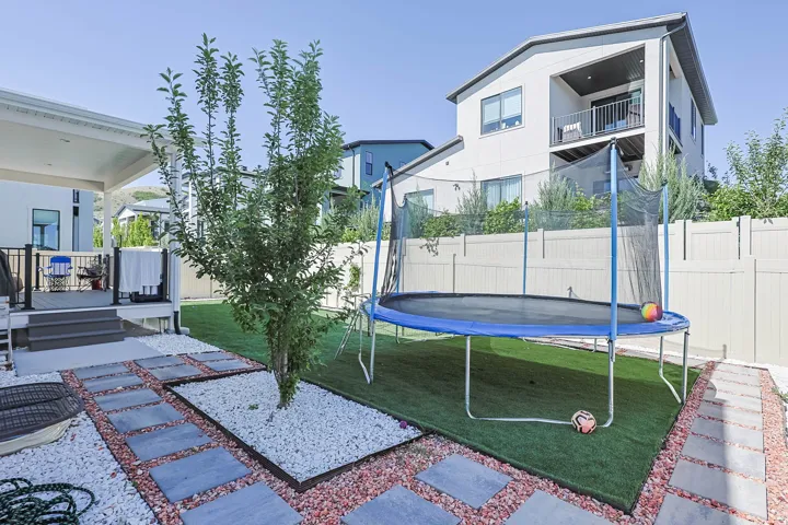 Expansive backyard featuring a covered patio, tiered deck, artificial turf, and a privacy fence