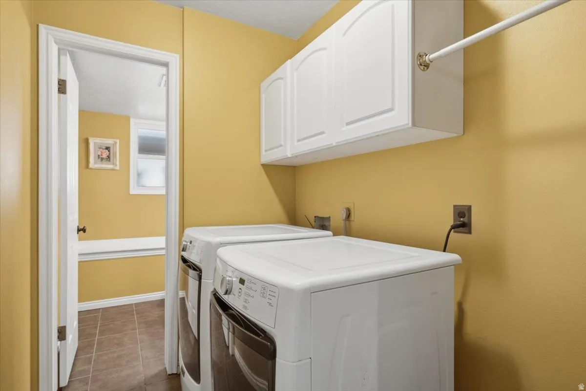 Laundry area featuring white cabinetry, a hanging rod, and tile flooring