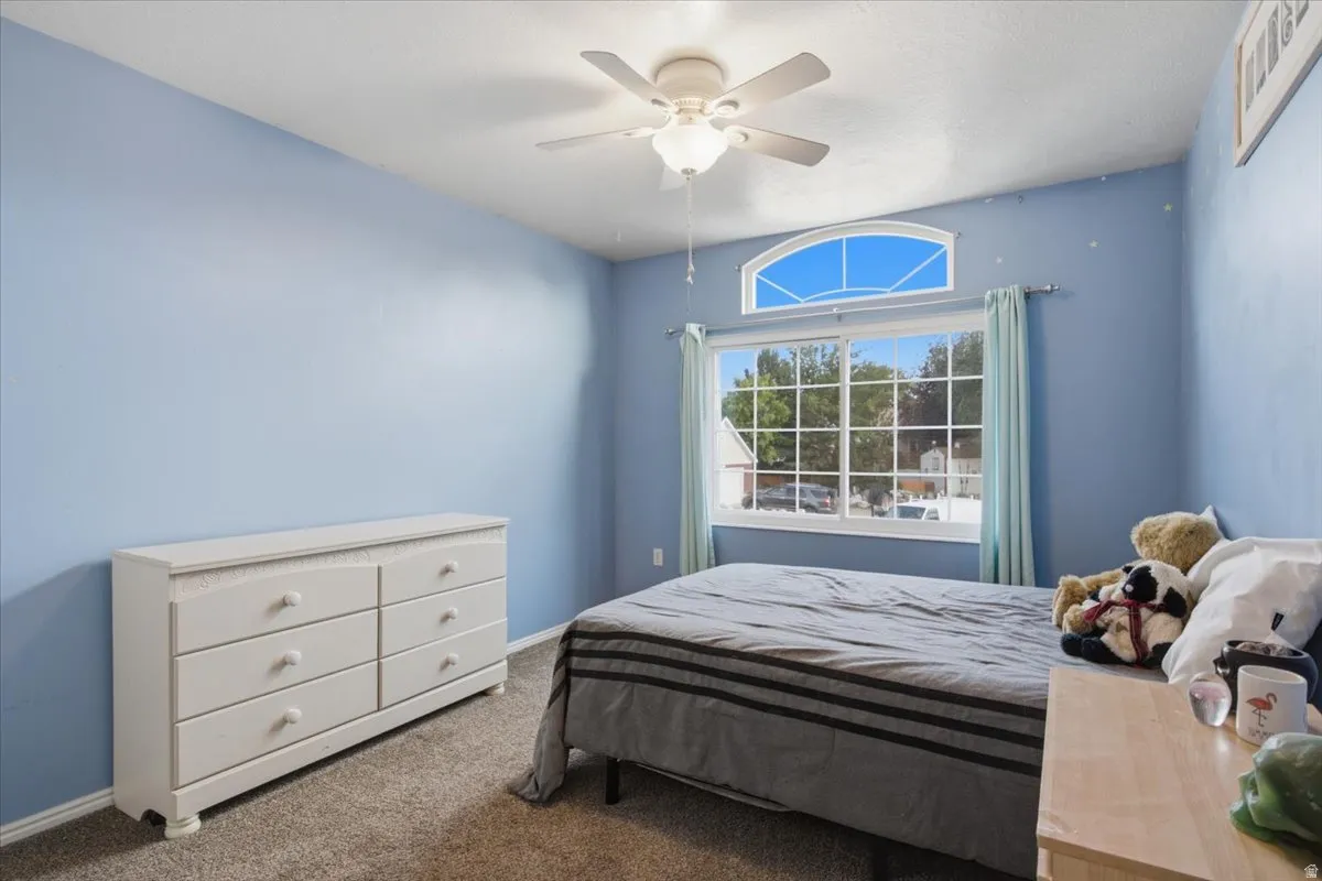 Carpeted flooring, vaulted ceiling, ceiling fan, large window, and arched transom window