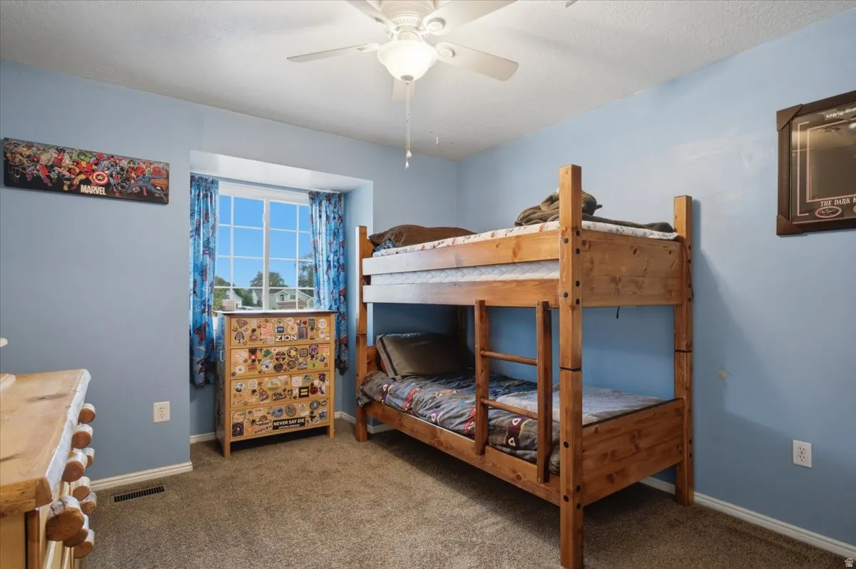 Carpeted flooring, window with exterior scenery, ceiling fan, and light blue wall finish