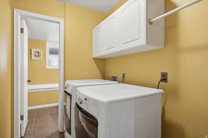 Laundry area featuring white cabinetry, a hanging rod, and tile flooring