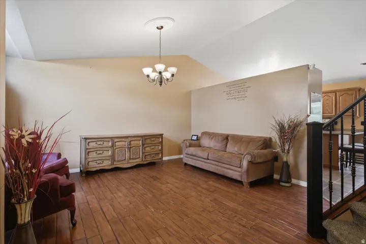 Vaulted ceiling with a flush-mount chandelier, wood-finish flooring, and a half-wall partition