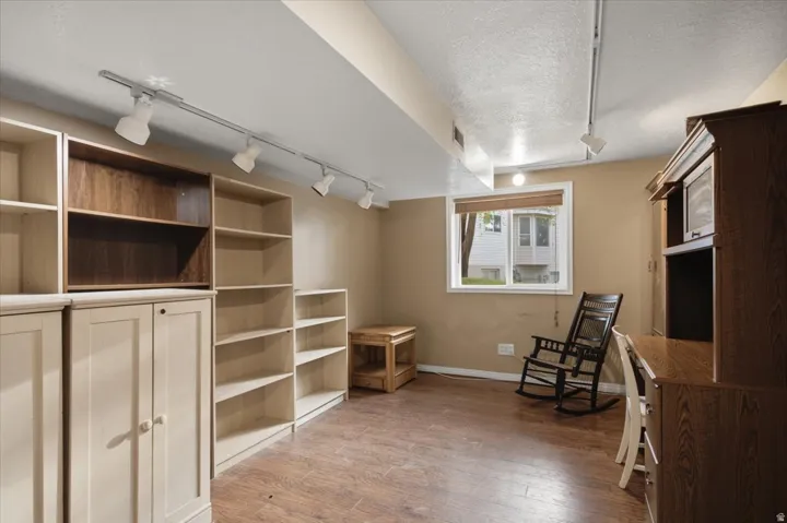 Integrated shelving units, wood-finish flooring, track lighting, and a single window