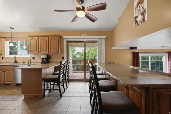 Kitchen with wood-finish cabinetry, tile flooring, and a ceiling fan with integrated lighting