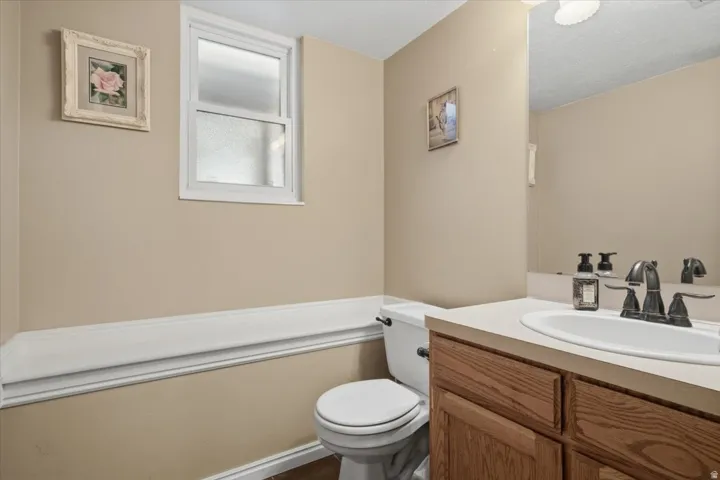 Neutral Bathroom with Wood-Finish Vanity, Dual Sink Countertop, and WainscotingThis bathroom features a wood-finish vanity with ample storage, a white dual-sink countertop, and matte black hardware