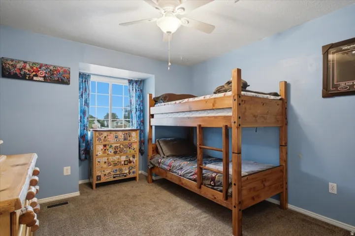Carpeted flooring, window with exterior scenery, ceiling fan, and light blue wall finish