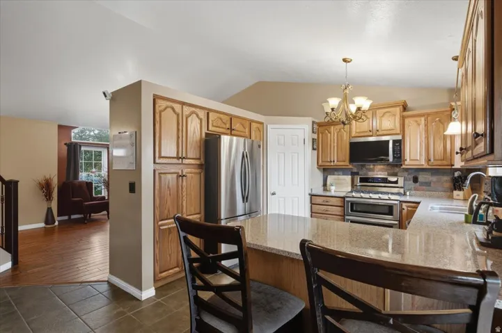 Kitchen featuring wood cabinetry, stainless steel appliances, an island with countertop, and tile flooring