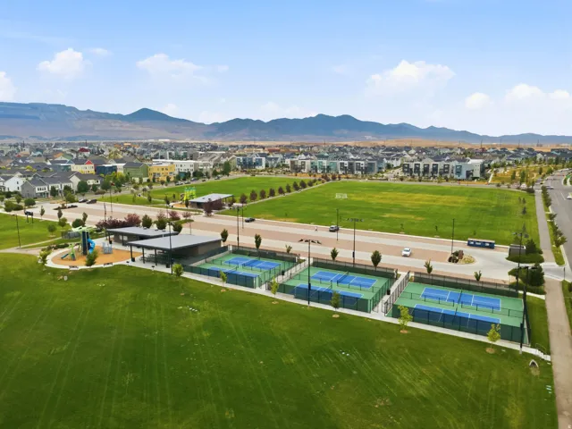 Expansive green space featuring multiple sports courts, a playground area, and covered shelters